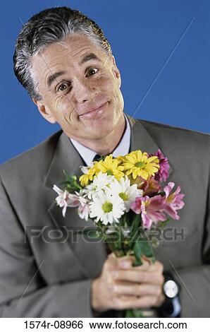 Stock Photograph - Portrait of a mid adult man holding a bouquet of flowers. Fotosearch