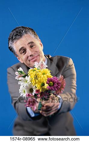 Portrait of a mid adult man holding a bouquet of flowers View Large Photo Image Stock Photography - Portrait of a mid adult man holding a bouquet of flowers. Fotosearch