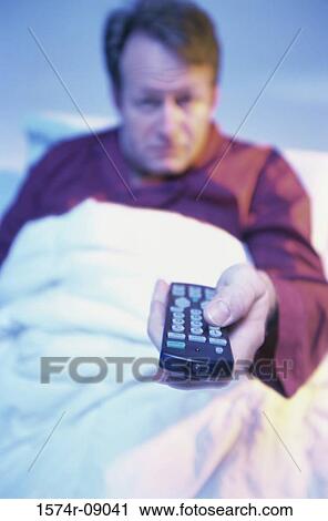 Portrait of a mid adult man lying in bed holding a remote control View Large Photo Image Stock Image - Portrait of a mid adult man lying in bed holding a remote control. Fotosearch
