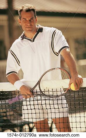 Portrait of a mid adult man standing on a tennis court View Large Photo Image Stock Image - Portrait of a mid adult man standing on a tennis court. Fotosearch