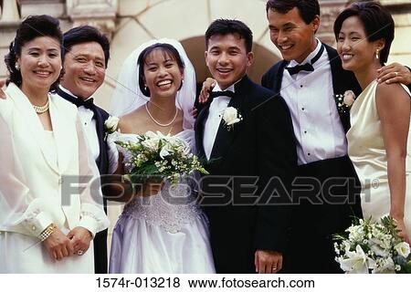 Stock Photo - Portrait of a newlywed couple standing with their parents and wedding guests. Fotosearch