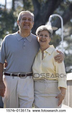 Stock Image - Portrait of a senior couple standing with their arms around each other. Fotosearch