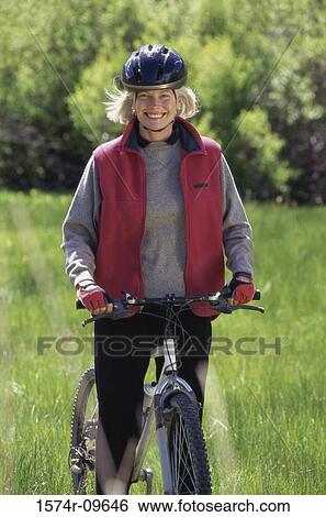 Portrait of a senior woman standing with a bicycle View Large Photo Image Stock Photograph - Portrait of a senior woman standing with a bicycle. Fotosearch