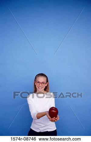 Portrait of a teenage girl holding an apple View Large Photo Image Stock Photograph - Portrait of a teenage girl holding an apple. Fotosearch