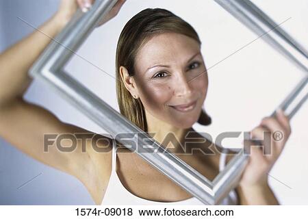 Portrait of a woman holding a picture frame View Large Photo Image Stock Photo - Portrait of a woman holding a picture frame. Fotosearch