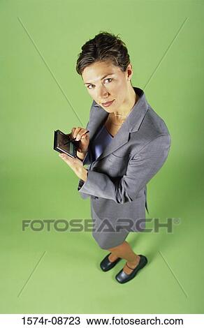 Stock Image - Portrait of a young businesswoman holding a hand held device. Fotosearch