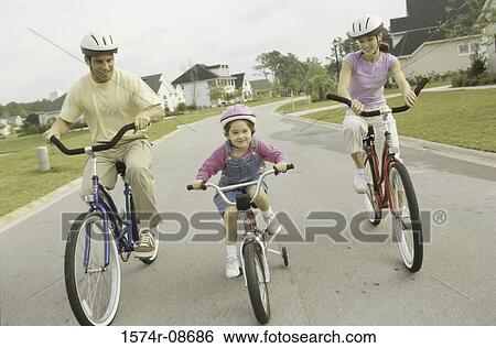 Portrait of a young couple cycling with their daughter View Large Photo Image Stock Photograph - Portrait of a young couple cycling with their daughter. Fotosearch