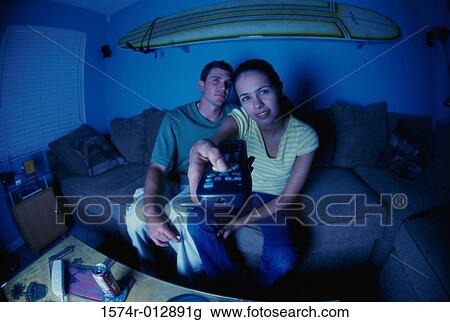 Portrait of a young couple sitting on a couch watching television View Large Photo Image Stock Image - Portrait of a young couple sitting on a couch watching television. Fotosearch