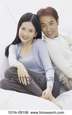 Portrait of a young couple sitting on a couch smiling View Large Photo Image Stock Photo - Portrait of a young couple sitting on a couch smiling. Fotosearch