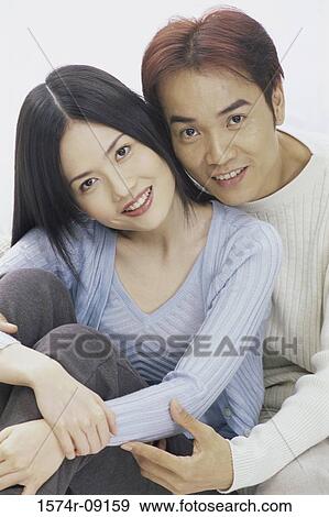 Stock Photo - Portrait of a young couple sitting on a couch smiling. Fotosearch