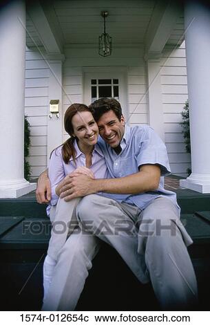 Stock Image - Portrait of a young couple sitting on the porch smiling. Fotosearch