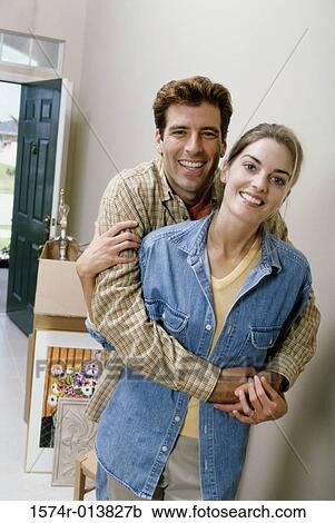Stock Image - Portrait of a young man embracing a young woman from behind. Fotosearch