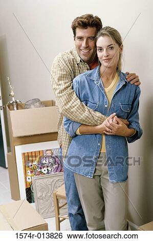 Stock Photograph - Portrait of a young man embracing a young woman from behind. Fotosearch