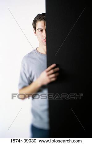 Portrait of a young man hiding behind a door View Large Photo Image Stock Image - Portrait of a young man hiding behind a door. Fotosearch
