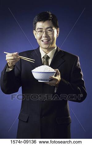 Portrait of a young man holding a bowl of rice View Large Photo Image Stock Photograph - Portrait of a young man holding a bowl of rice. Fotosearch