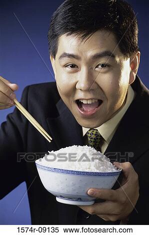 Stock Photography - Portrait of a young man holding a bowl of rice. Fotosearch