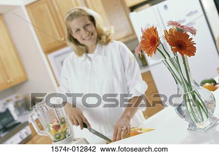 Stock Image - Portrait of a young pregnant woman cutting fruit. Fotosearch