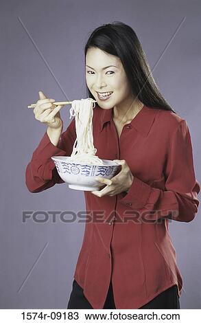 Portrait of a young woman eating a bowl of noodles View Large Photo Image Stock Image - Portrait of a young woman eating a bowl of noodles. Fotosearch