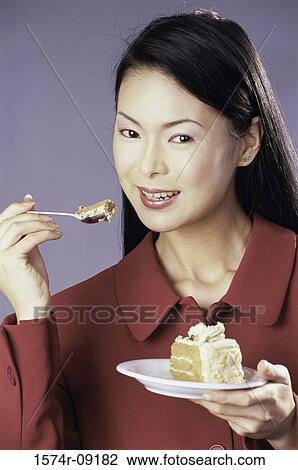 Stock Image - Portrait of a young woman eating a slice of cake. Fotosearch