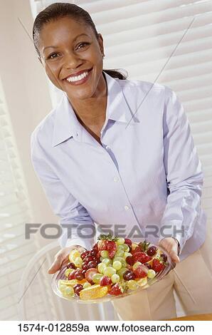 Portrait of a young woman holding a tray of mixed fruit View Large Photo Image Stock Image - Portrait of a young woman holding a tray of mixed fruit. Fotosearch