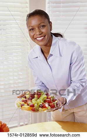 Portrait of a young woman holding a plate of fruit View Large Photo Image Stock Image - Portrait of a young woman holding a plate of fruit. Fotosearch