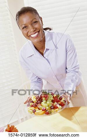 Portrait of a young woman holding a plate of fruit View Large Photo Image Stock Image - Portrait of a young woman holding a plate of fruit. Fotosearch