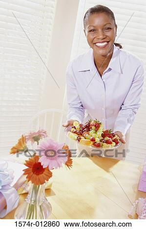 Portrait of a young woman holding a tray of mixed fruit View Large Photo Image Stock Image - Portrait of a young woman holding a tray of mixed fruit. Fotosearch