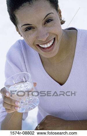 Stock Image - Portrait of a young woman holding a glass of water. Fotosearch