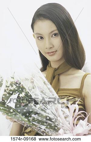 Portrait of a young woman holding a bouquet of flowers View Large Photo Image Stock Photo - Portrait of a young woman holding a bouquet of flowers. Fotosearch
