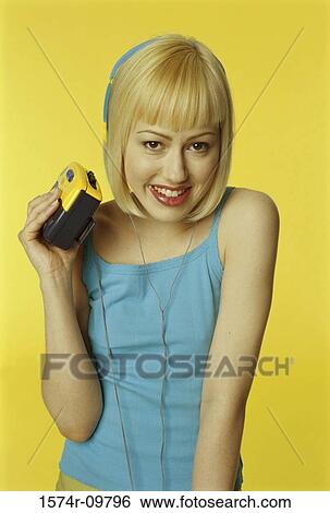 Stock Photograph - Portrait of a young woman holding a music player. Fotosearch