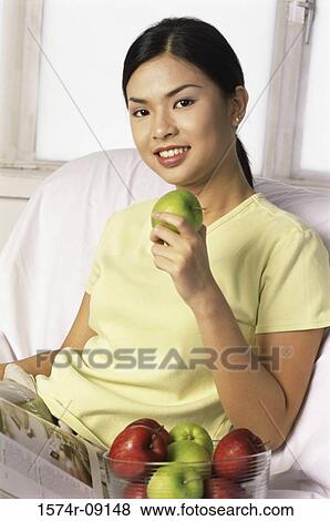 Stock Photo - Portrait of a young woman holding an apple. Fotosearch