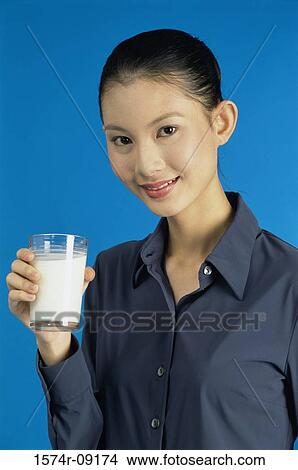 Picture - Portrait of a young woman holding out a glass of milk. Fotosearch
