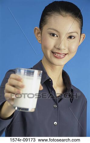 Portrait of a young woman holding out a glass of milk View Large Photo Image Stock Image - Portrait of a young woman holding out a glass of milk. Fotosearch