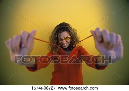 Portrait of a young woman holding strings of her hooded jacket View Large Photo Image Stock Photo - Portrait of a young woman holding strings of her hooded jacket. Fotosearch