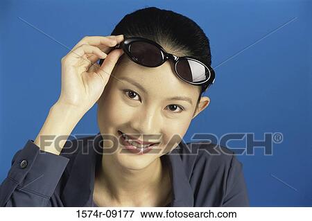 Portrait of a young woman holding sunglasses View Large Photo Image Stock Photo - Portrait of a young woman holding sunglasses. Fotosearch