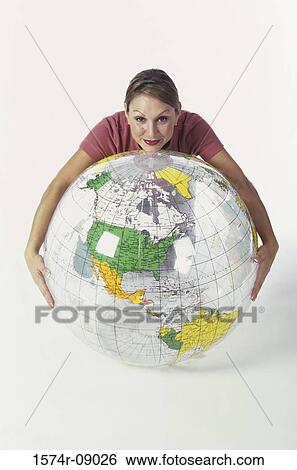 Stock Photograph - Portrait of a young woman leaning on an inflatable globe. Fotosearch