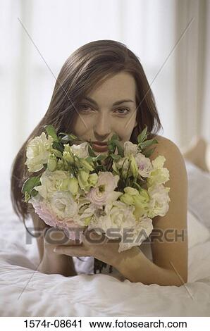 Portrait of a young woman lying down holding a bouquet of flowers View Large Photo Image Stock Image - Portrait of a young woman lying down holding a bouquet of flowers. Fotosearch