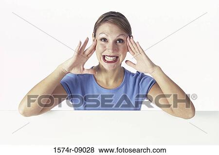 Portrait of a young woman making face behind a wall View Large Photo Image Stock Photo - Portrait of a young woman making face behind a wall. Fotosearch