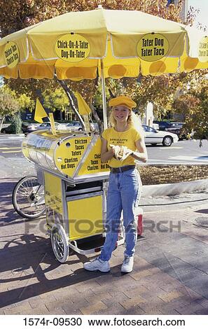Portrait of a young woman standing on the sidewalk selling hot dogs View Large Photo Image Stock Image - Portrait of a young woman standing on the sidewalk selling hot dogs. Fotosearch