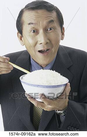 Stock Image - Portrait of man holding a bowl of rice. Fotosearch