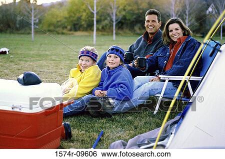 Portrait of parents and their two daughters sitting at a park View Large Photo Image Stock Photograph - Portrait of parents and their two daughters sitting at a park. Fotosearch