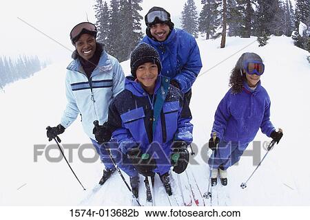 Stock Image - Portrait of parents standing with their two children in snow. Fotosearch