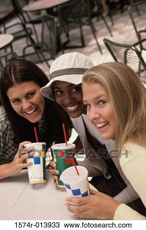 Stock Image - Portrait of three teenage girls sitting in a restaurant. Fotosearch