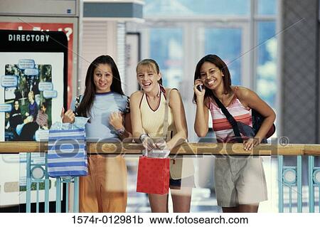 Stock Image - Portrait of three teenage girls standing in a shopping mall. Fotosearch