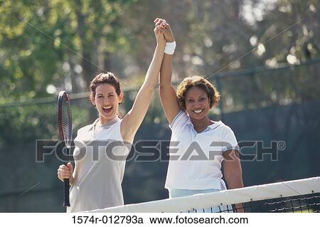 Stock Image - Portrait of two mid adult women cheering after winning a match. Fotosearch
