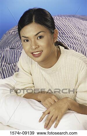 Portrait of young woman lying on a bed smiling View Large Photo Image Stock Photo - Portrait of young woman lying on a bed smiling. Fotosearch