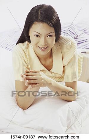 Portrait of young woman lying on a bed smiling View Large Photo Image Stock Photo - Portrait of young woman lying on a bed smiling. Fotosearch