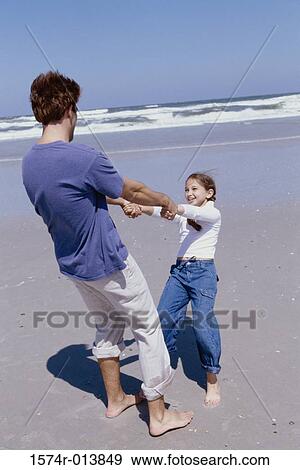 Rear view of a father playing with his daughter on the beach View Large Photo Image Stock Photo - Rear view of a father playing with his daughter on the beach. Fotosearch