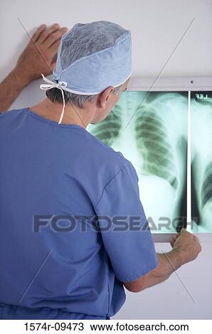 Stock Image - Rear view of a male doctor examining an X-ray film. Fotosearch