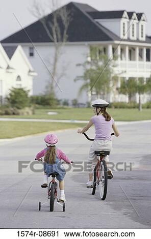 Rear view of a mother and daughter riding bicycles View Large Photo Image Stock Image - Rear view of a mother and daughter riding bicycles. Fotosearch